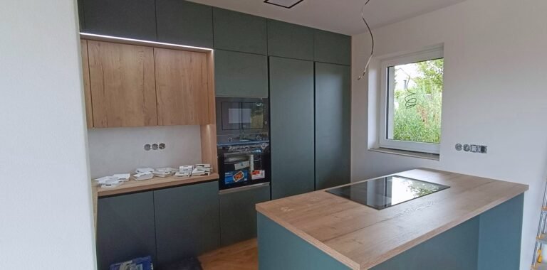 Tmavě zelená kuchyně s ostrůvkem a dřevěnou pracovní deskou