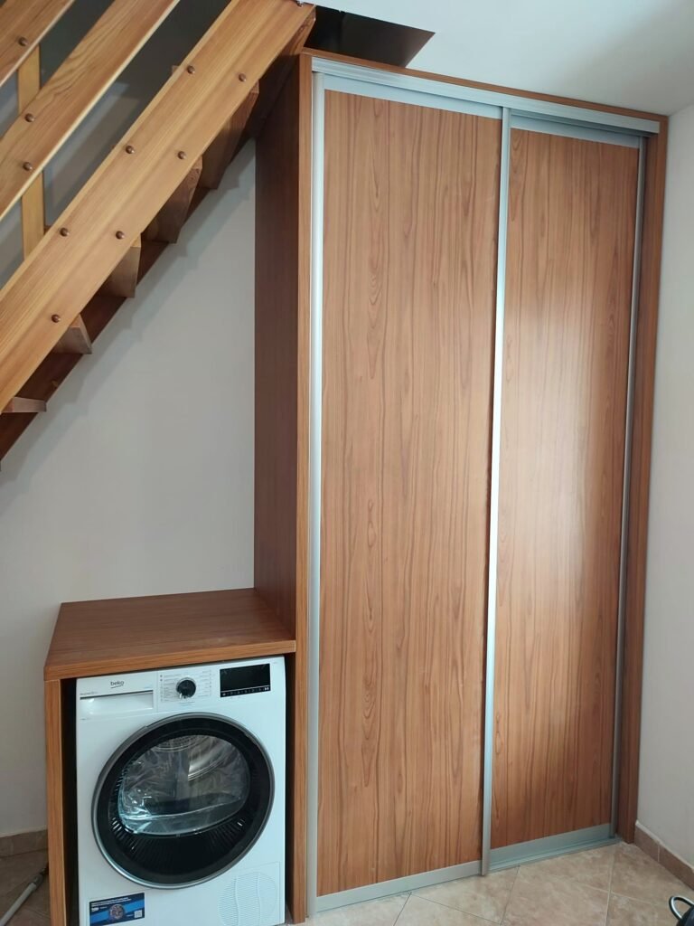 Vestavěná skříň s posuvnými dveřmi pod schody vedle pračky a sušičky